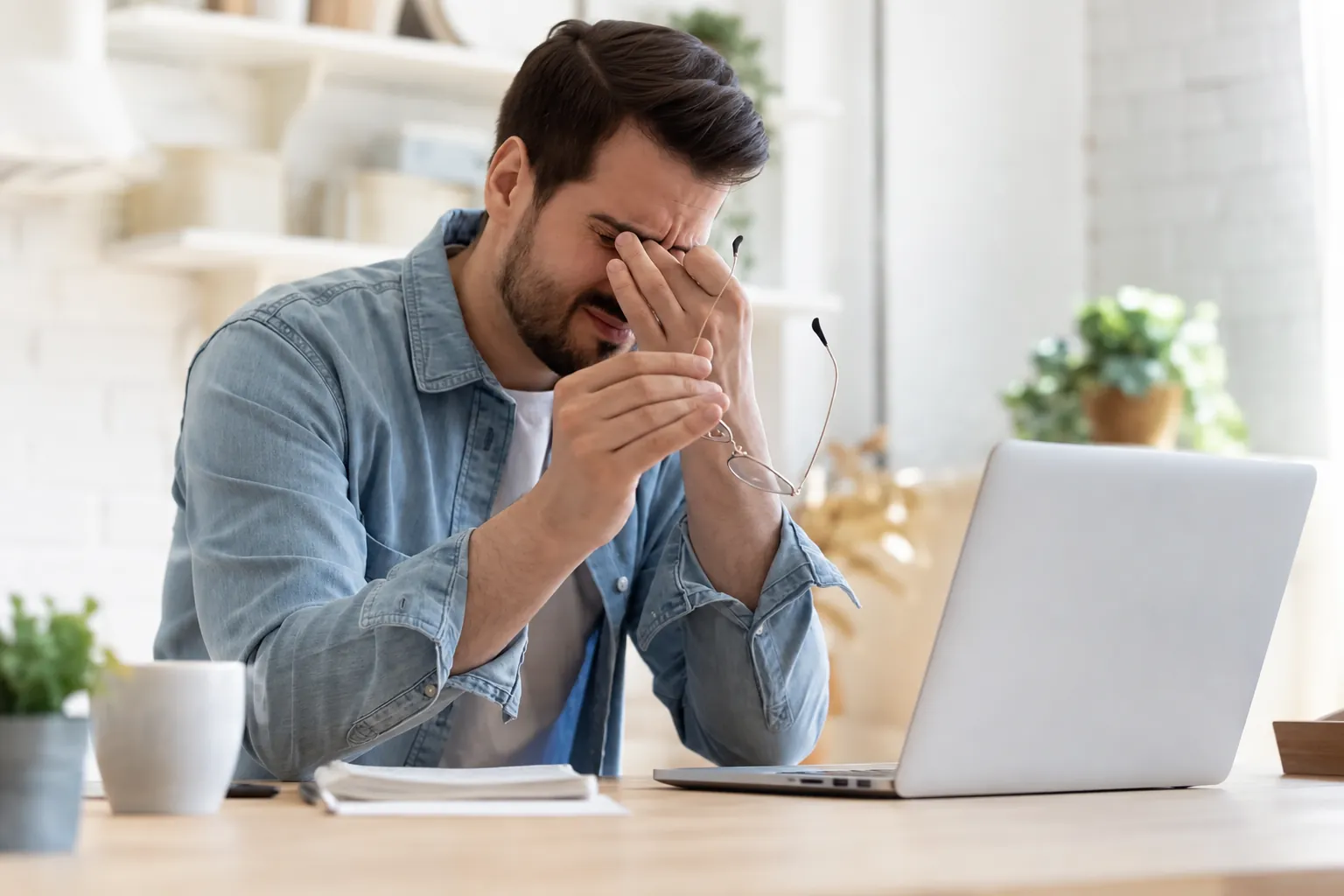 Hombre cansado se frota los ojos frente a su computador